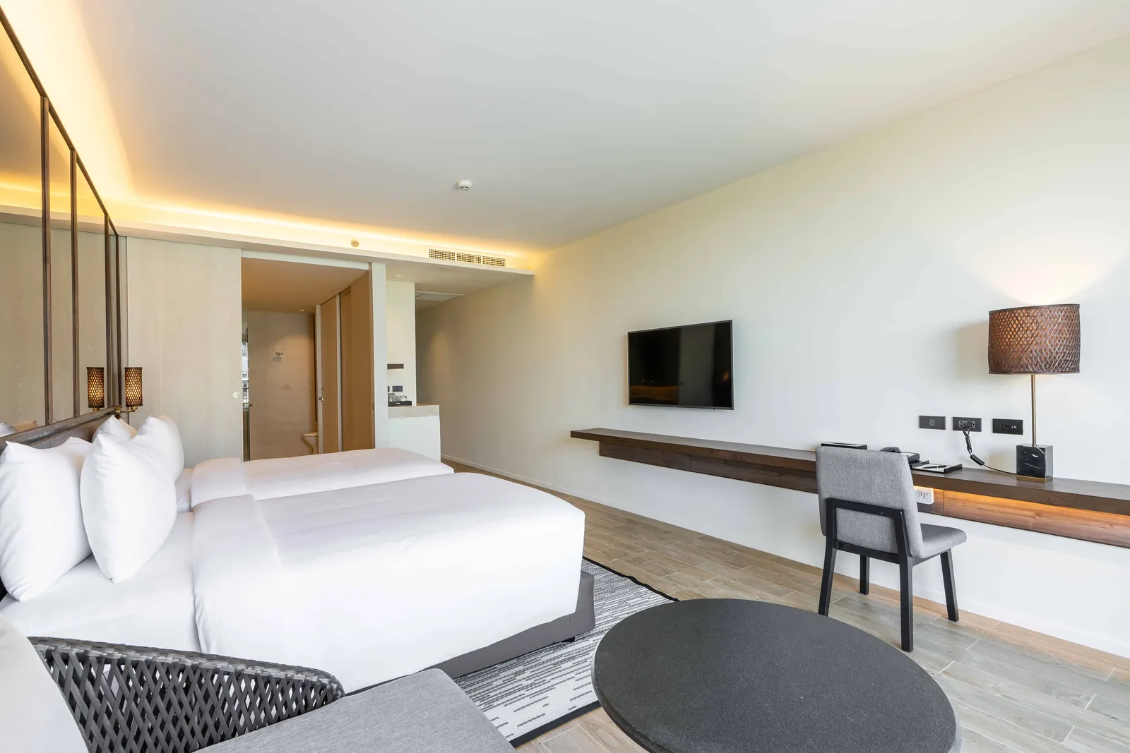Deluxe twin room with two single beds, a long desk running the length of the wall, a work chair and a wall-mounted TV